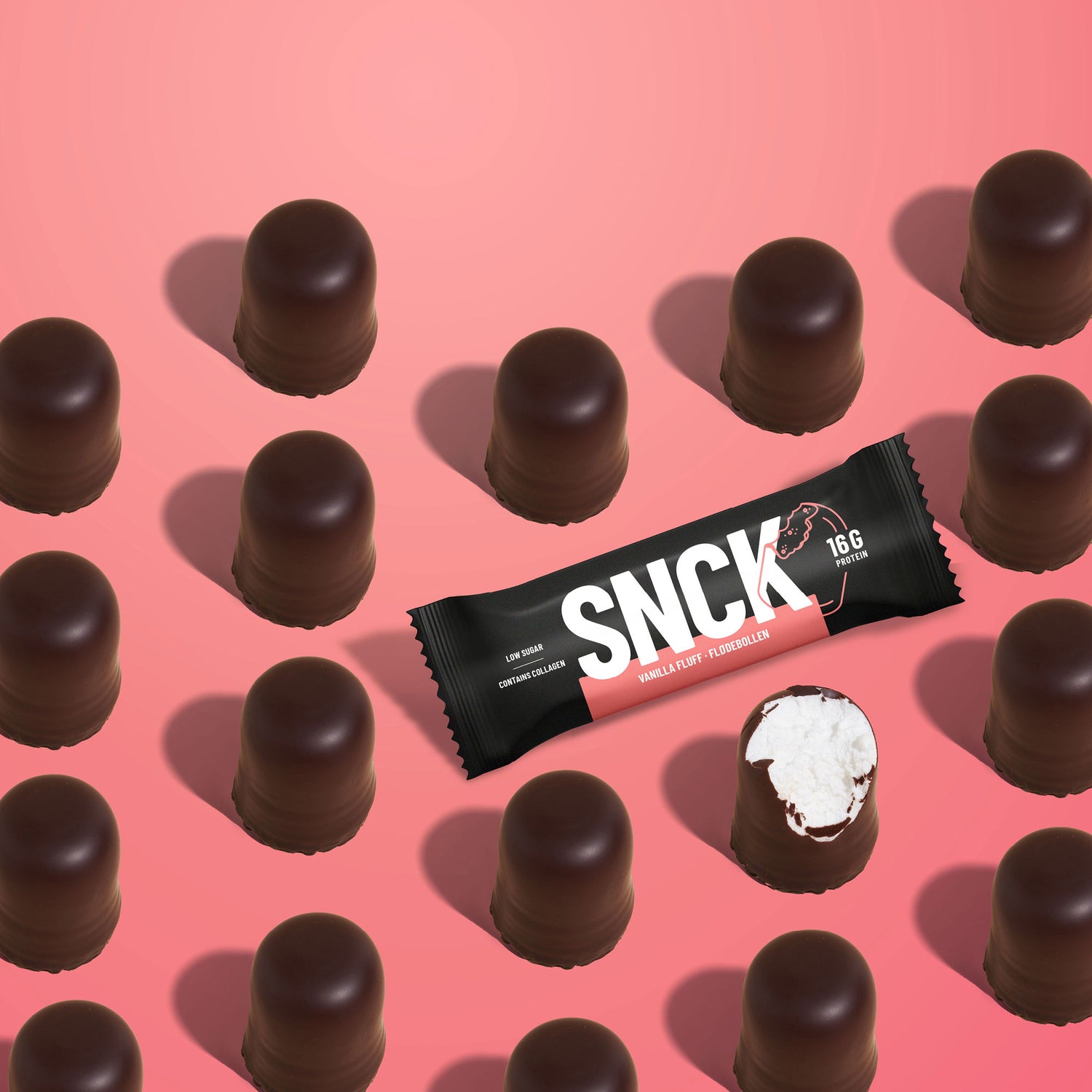 Chocolate-covered candies with a SNCK protein bar on a pink background